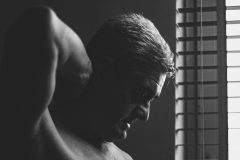 “Fine art portrait of thinking man in a minimal setting, focusing on stillness, light, and presence.”