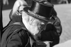Black and white street photograph capturing a quietman playing music, candid moment in public space.